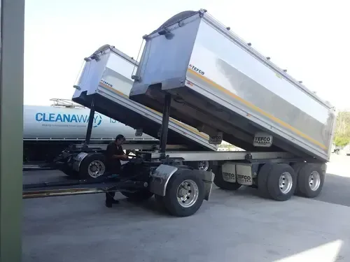 A dump truck is parked next to a cleanaway tank A dump truck is parked next to a cleanaway tank