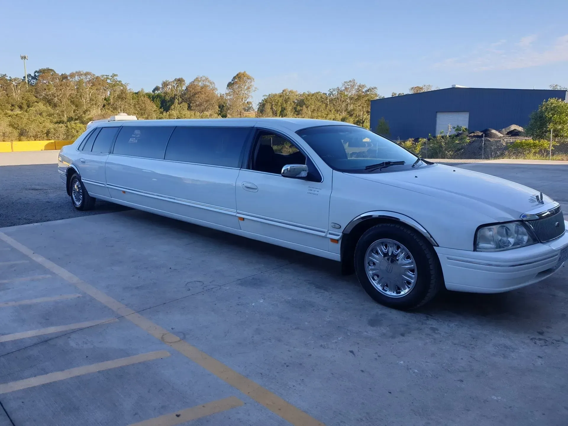 A white limousine is parked in a parking lot.