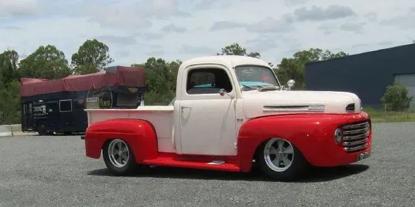 A white and red truck is parked in front of a building