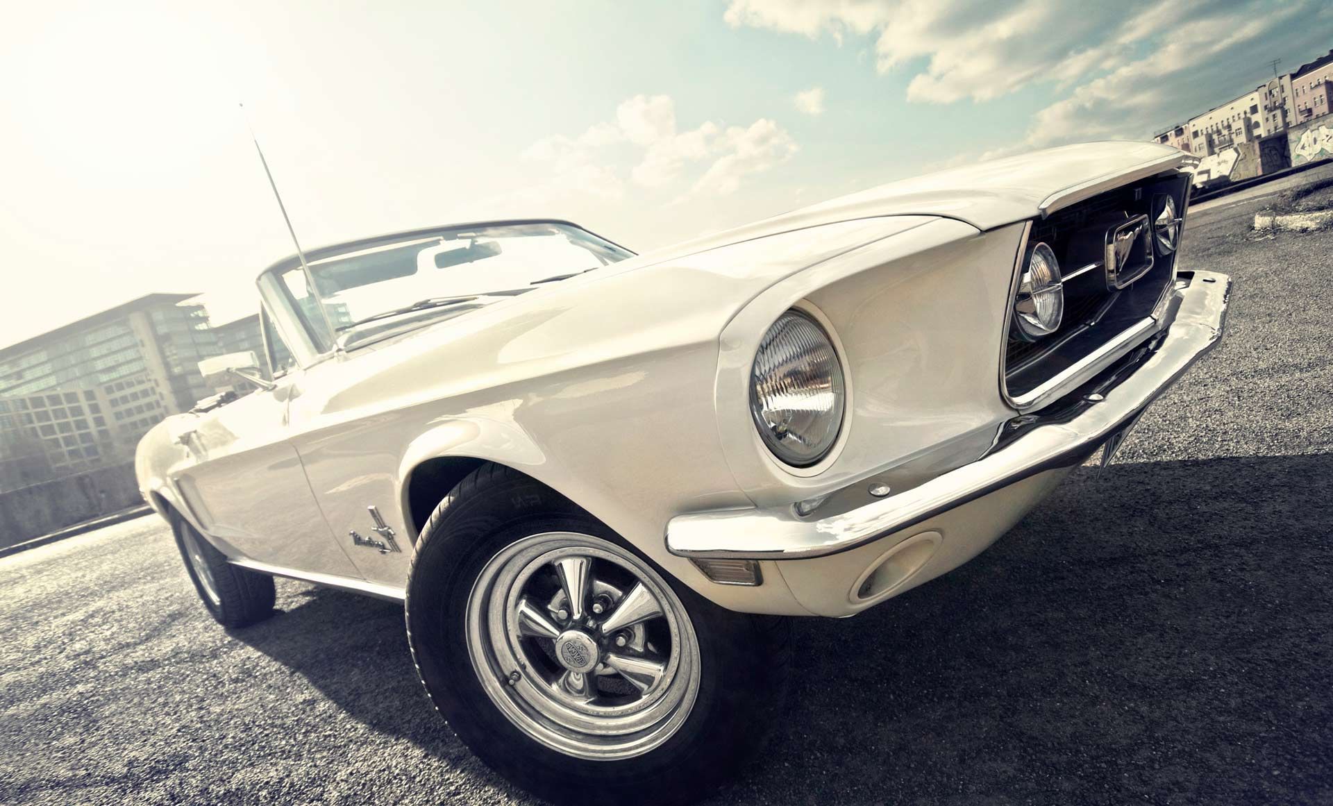 A white mustang convertible is parked on the side of the road.