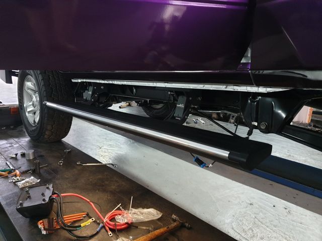 A purple truck is being worked on in a garage