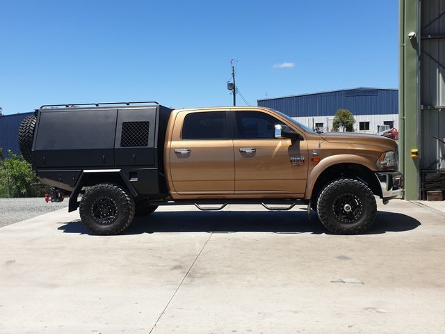 A truck with a black canopy is parked in a parking lot.