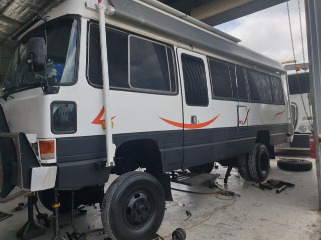 A white bus is sitting on a jack in a garage