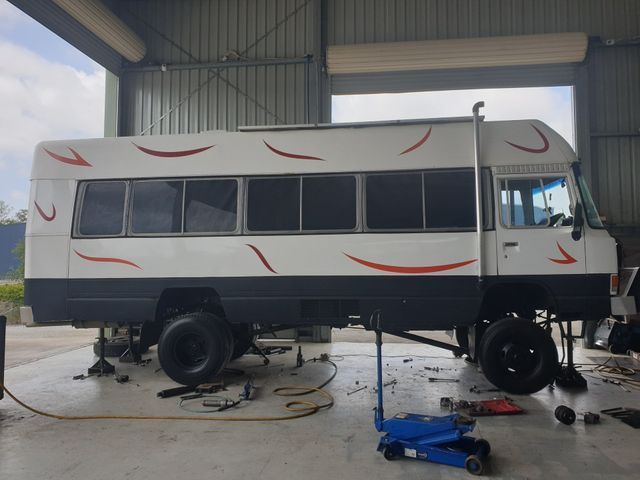 A white bus is being worked on in a garage