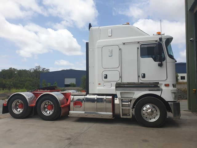 A white semi truck is parked in front of a building