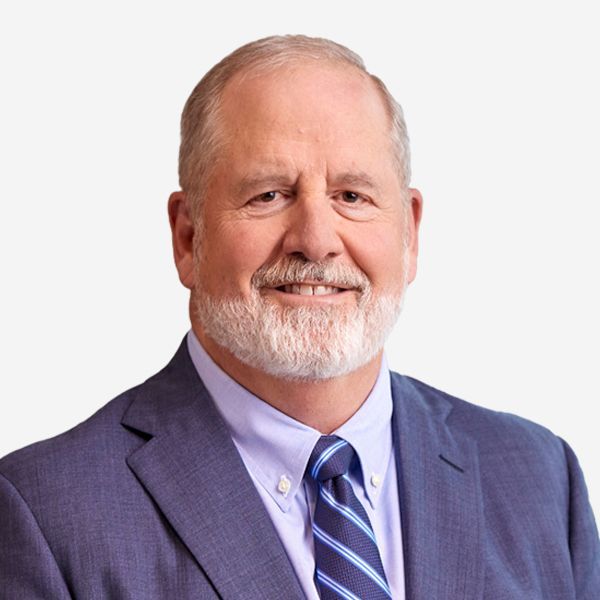 Man with gray beard, smiling, wearing a blue suit and tie.