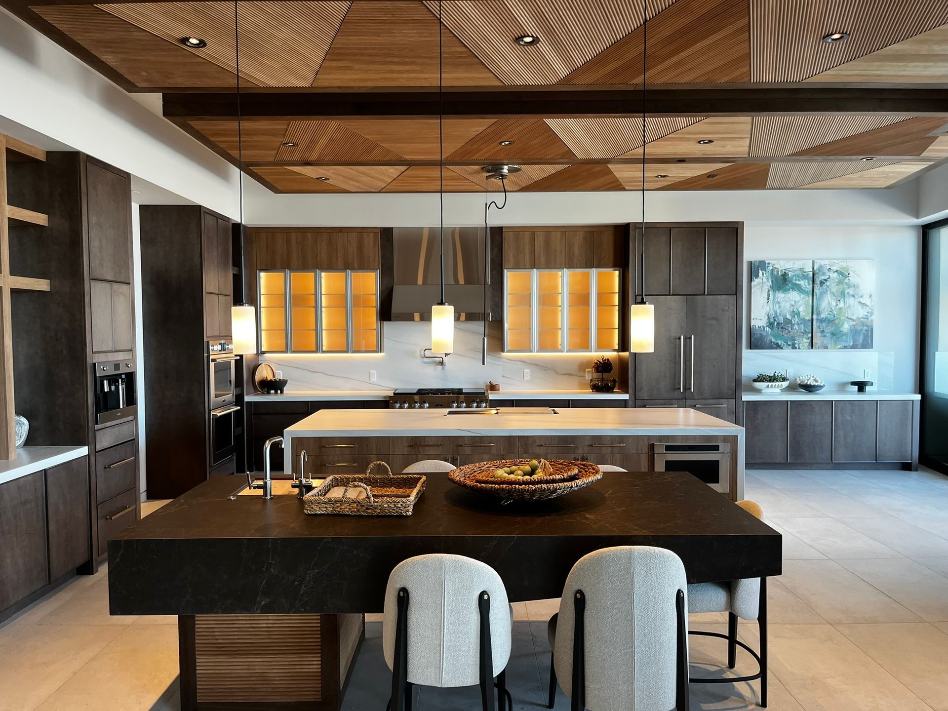 Modern luxury kitchen with dark wood cabinetry, marble countertops, and geometric wood ceiling design.