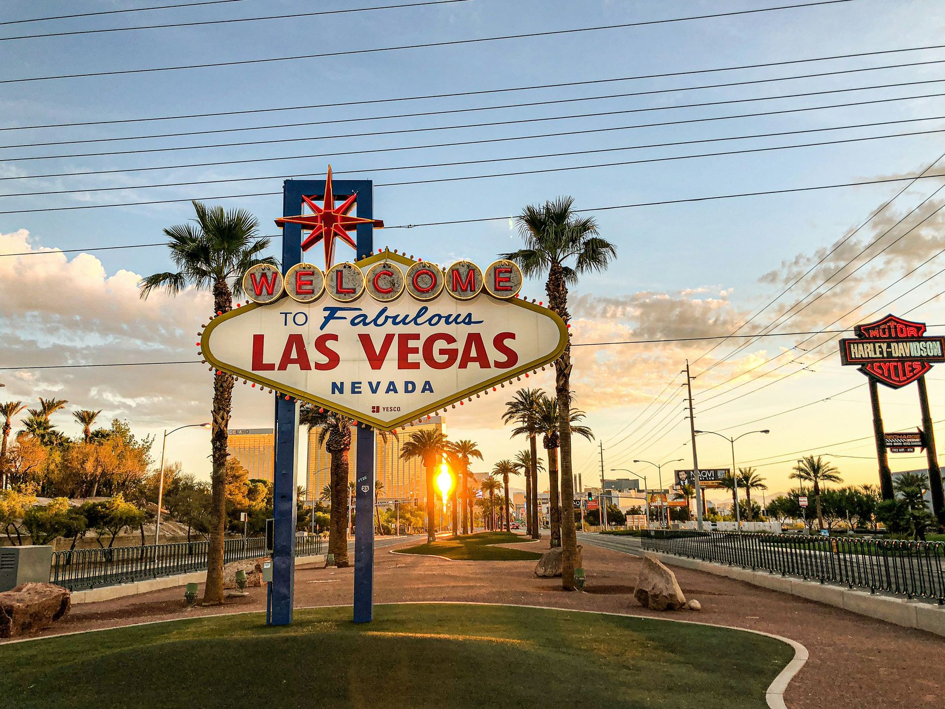 Iconic 'Welcome to Fabulous Las Vegas' sign at sunrise with palm trees and a clear sky in the background.