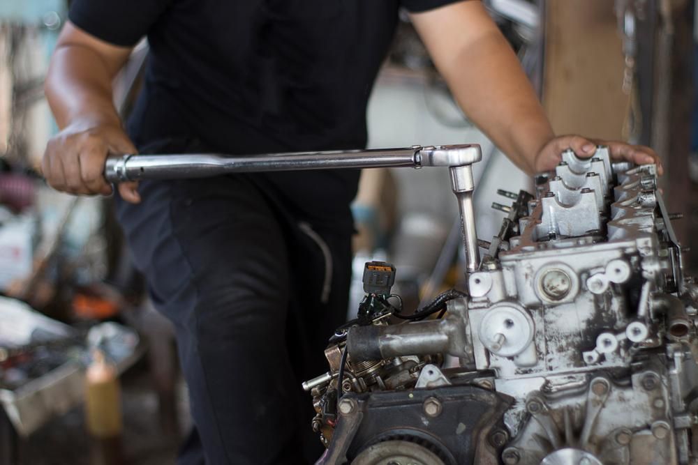 A Man Is Working On A Car Engine With A Wrench — Adrians Mechanical Services In Warana, QLD