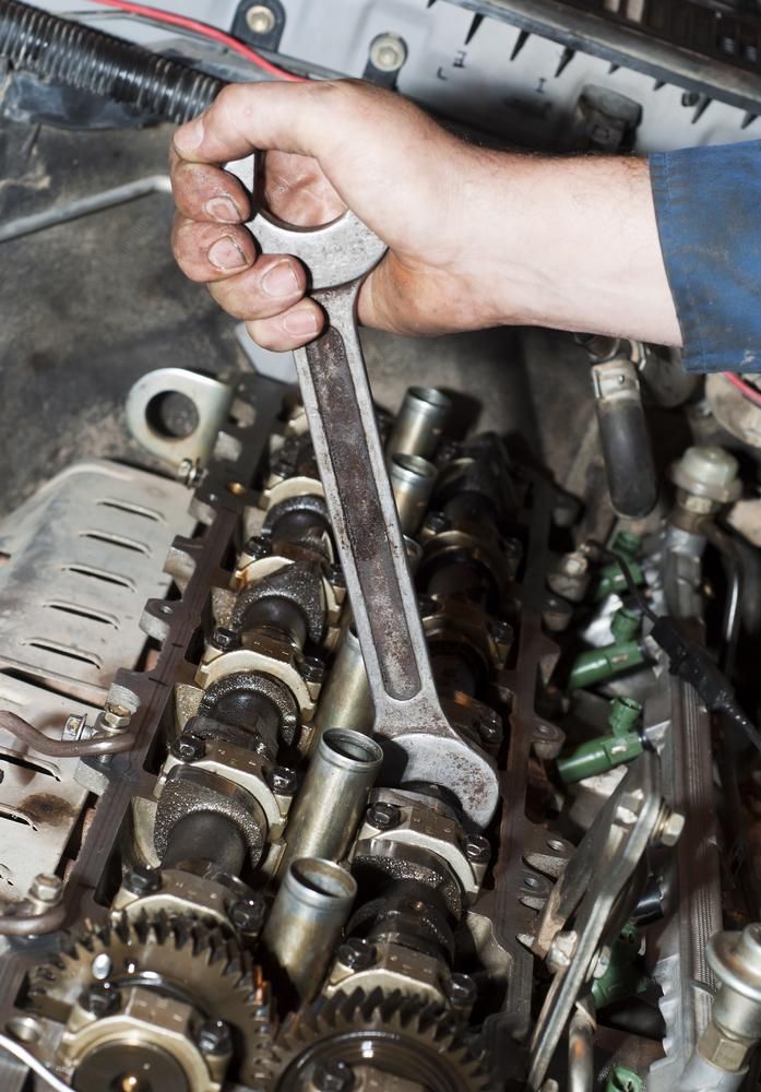 A Person Is Working On A Car Engine With A Wrench — Adrians Mechanical Services In Warana, QLD