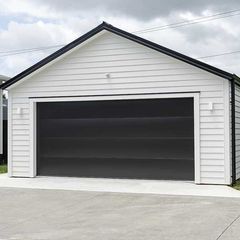 Typical double detached white garage with black tilt-up retractable raised panel metal door and gable metal roof 
