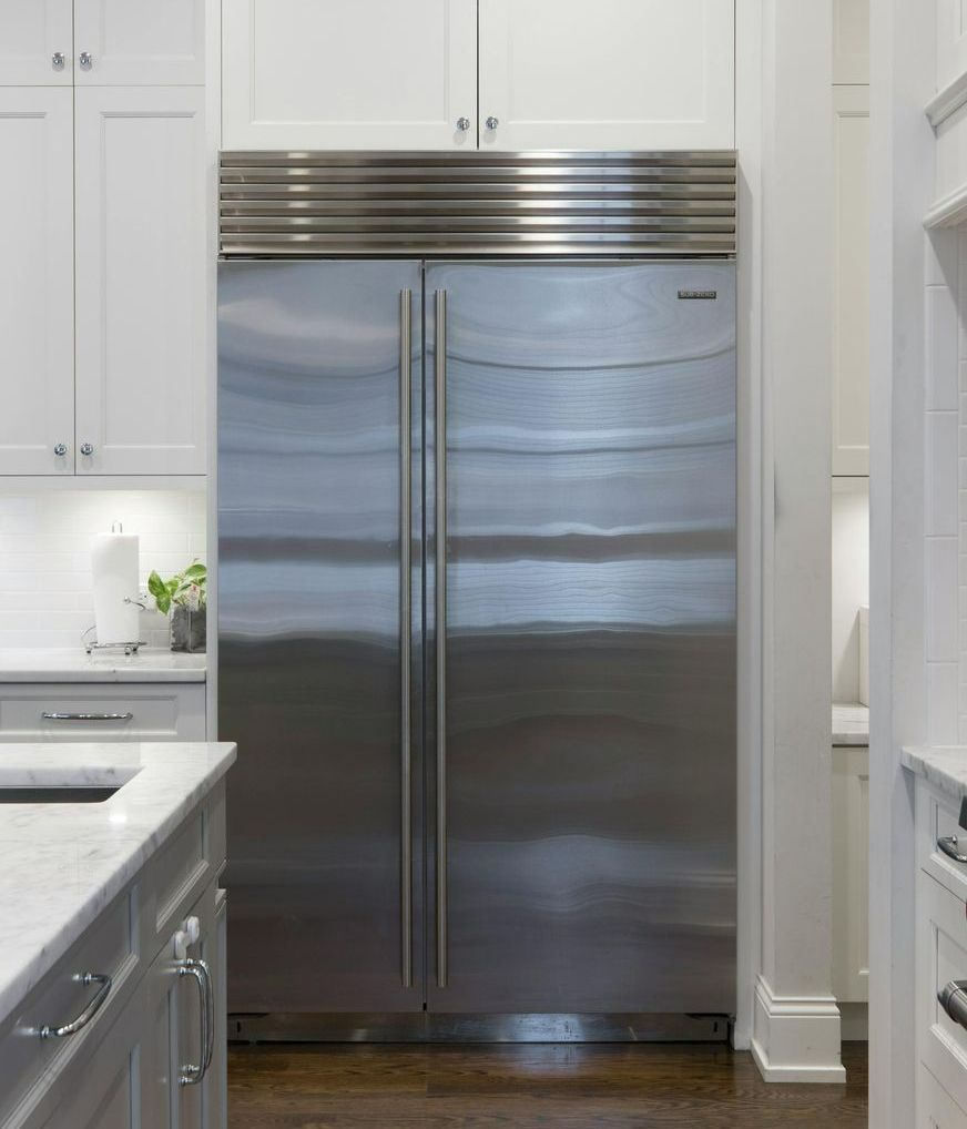 A stainless steel refrigerator in a kitchen with white cabinets