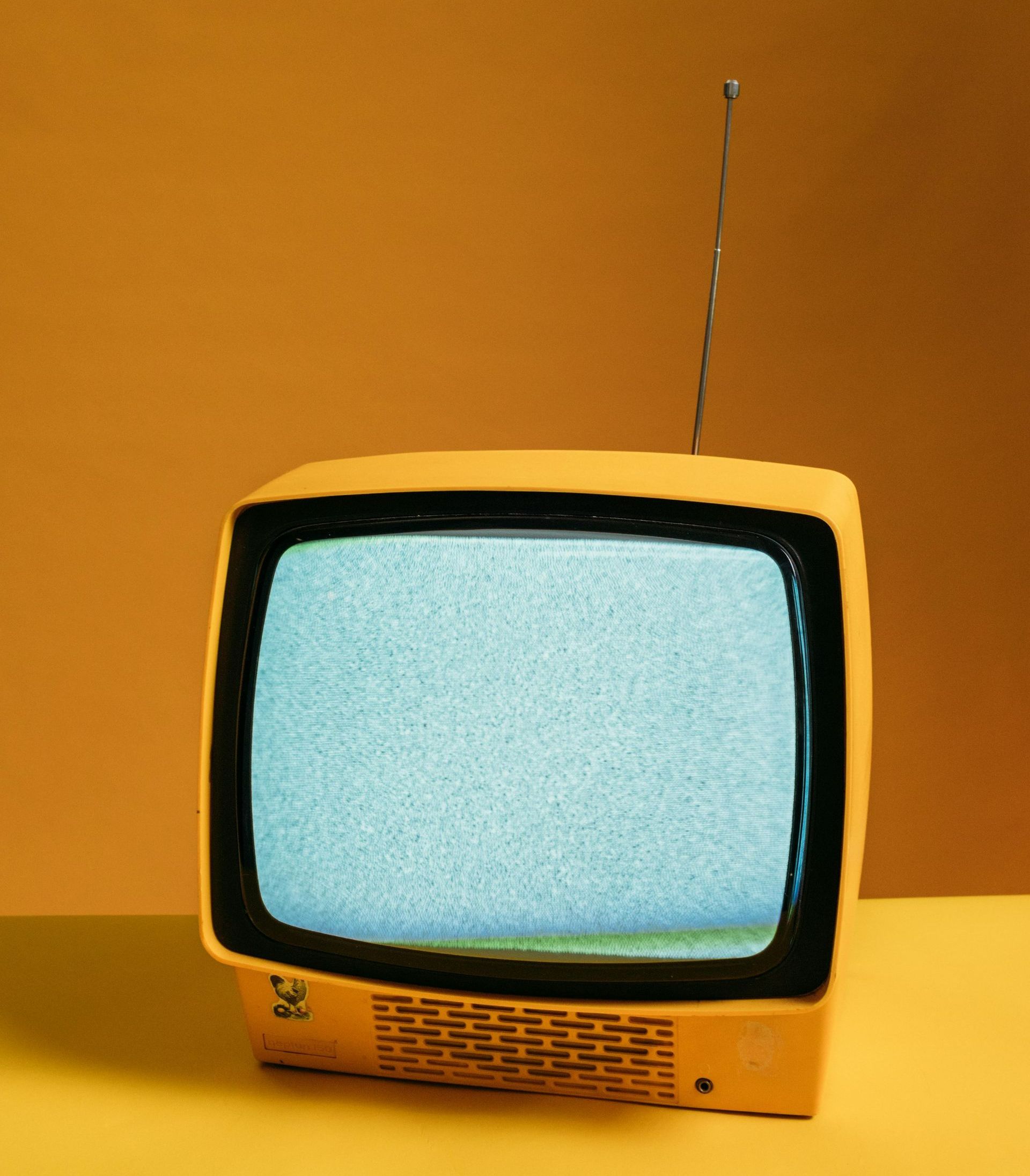 A yellow television is sitting on a yellow table.