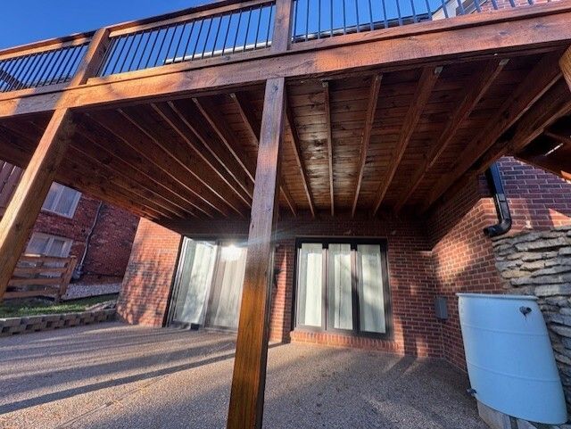 View from below a wooden deck; brick building beneath; blue sky overhead.