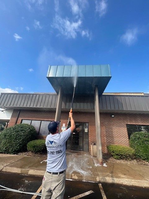 A Man Is Cleaning the Roof of A Building with A High Pressure Washer. - Bourbon City Softwash - Louisville, KY
