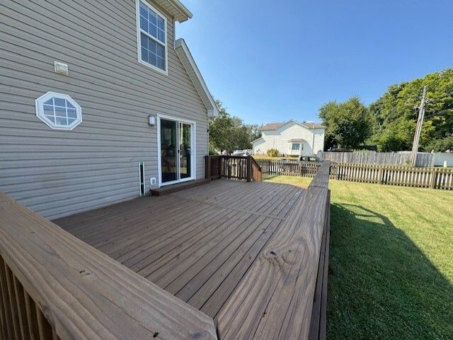 Backyard deck with wooden railing and siding of a house, sunny day.