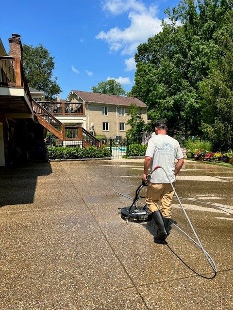 A Man Is Using a Machine to Clean a Driveway  - Bourbon City Softwash - Louisville, KY