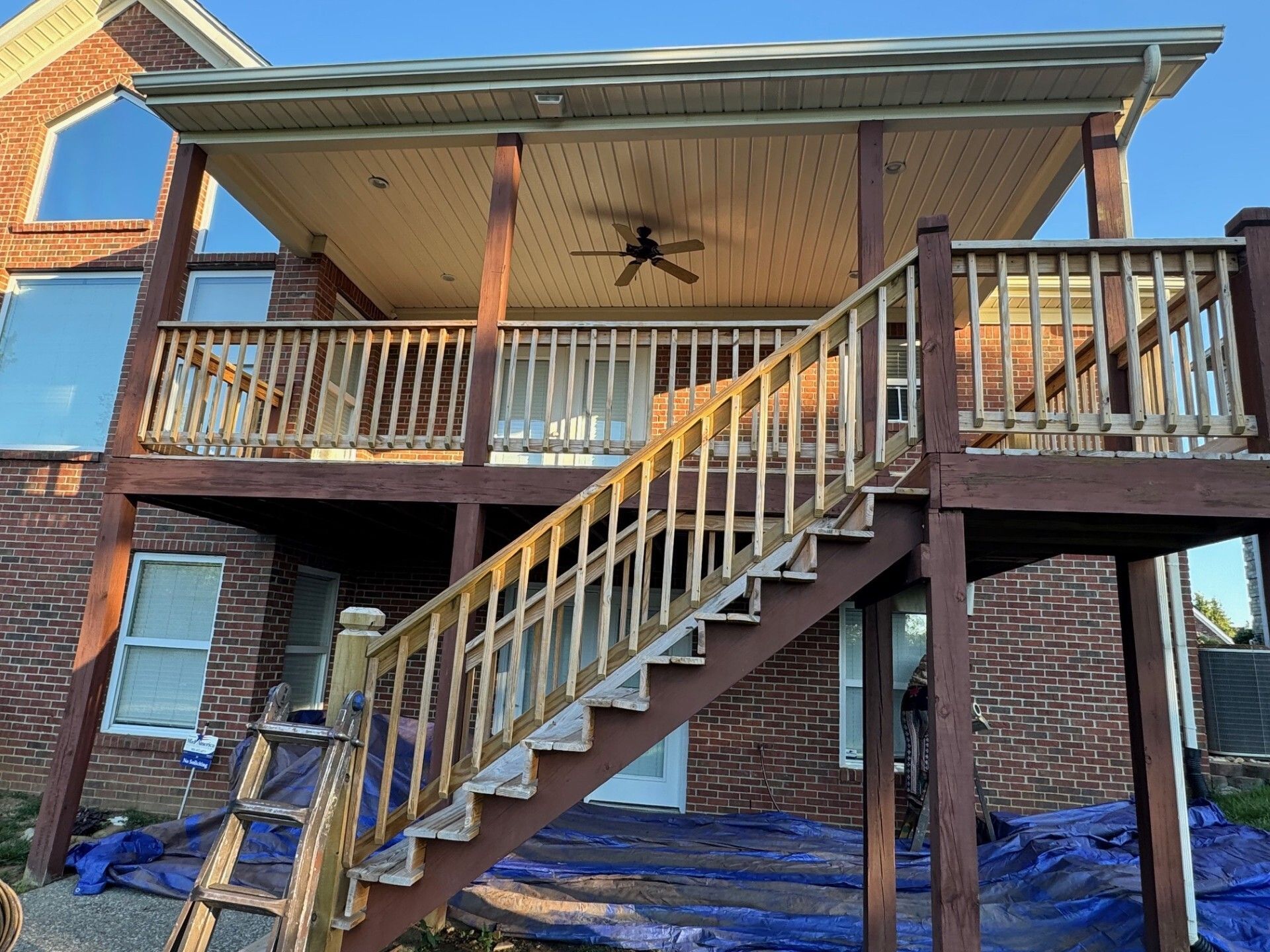 Wooden deck with stairs, covered patio, brick house.