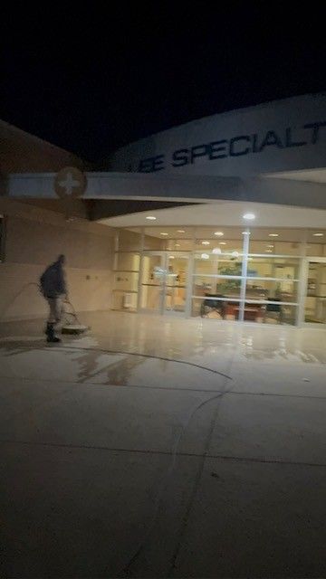 Person sweeping outside a building at night; 