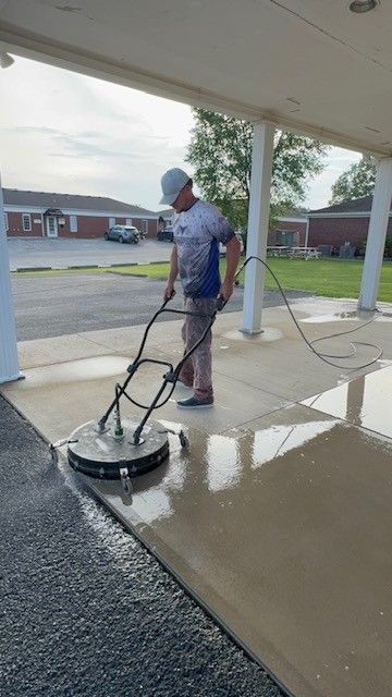 Man using a surface cleaner on a concrete surface outside a building.