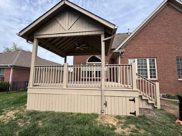 Wooden deck with a covered sitting area attached to a brick house. Beige and brown tones.