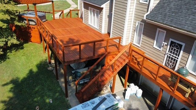 Wooden deck attached to a house with steps, stained orange, overlooking a grassy yard.