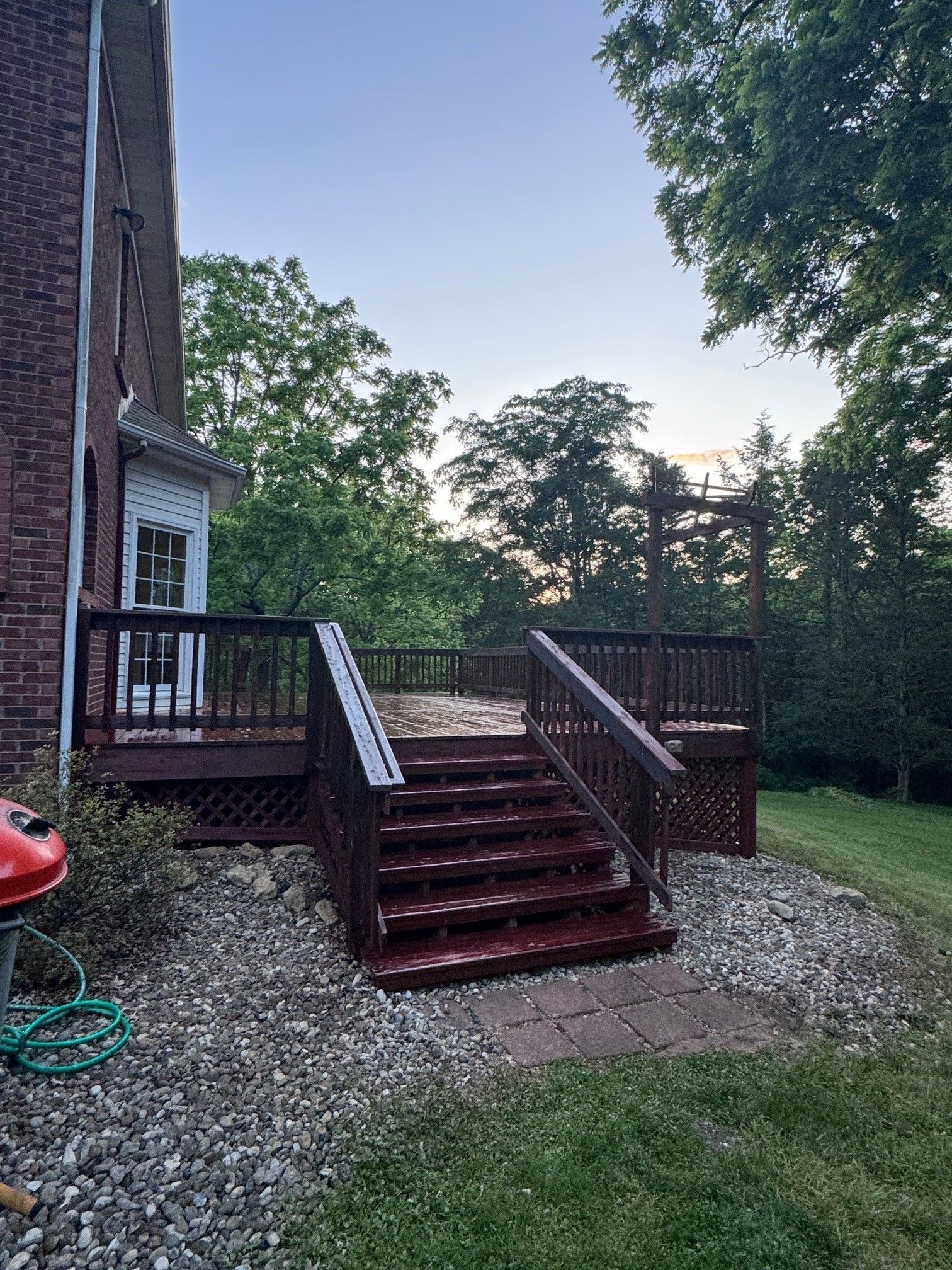 A wooden deck with stairs leading up to it is in the backyard of a house. - Bourbon City Softwash - Louisville, KY