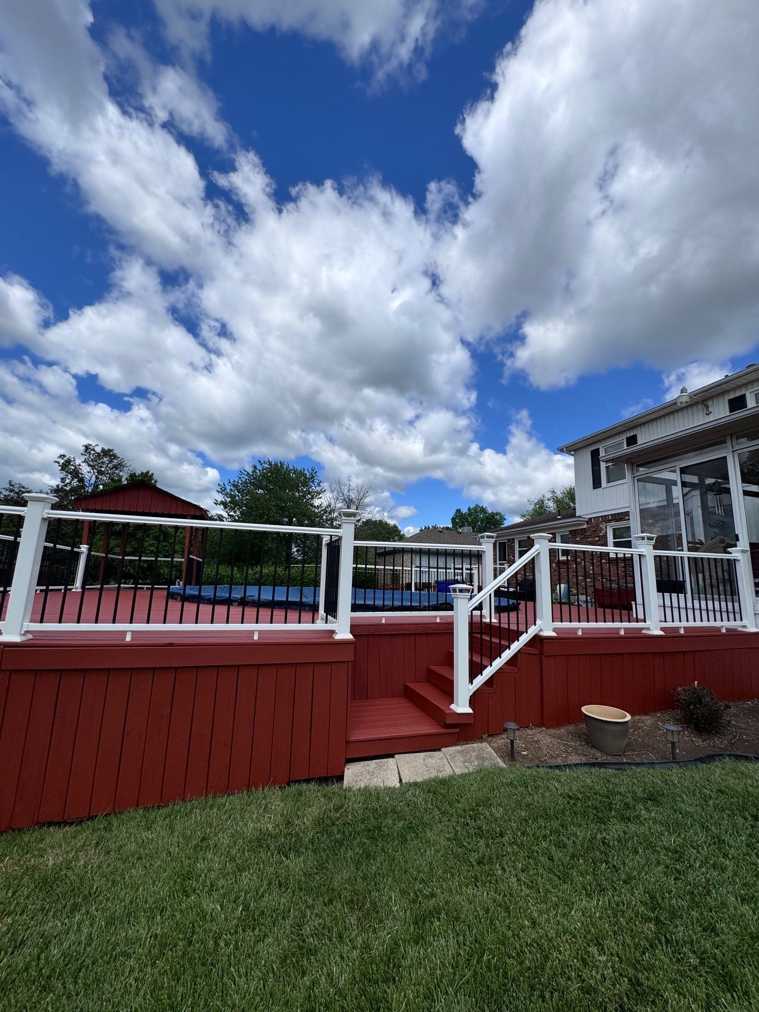 A red deck with white railings and stairs next to a house. - Bourbon City Softwash - Louisville, KY