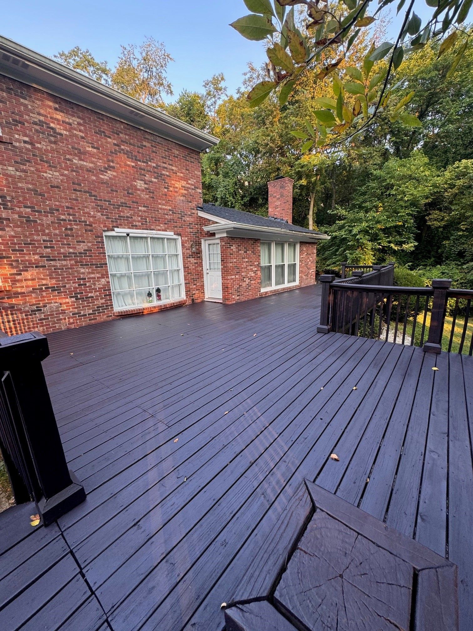 There is a large wooden deck in front of a brick house. - Bourbon City Softwash - Louisville, KY
