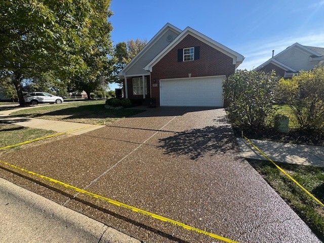 House with brown concrete driveway; yellow caution tape along edges, blue sky.