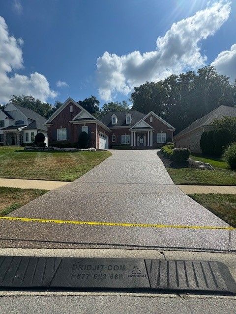 Brick house with a long driveway on a sunny day.