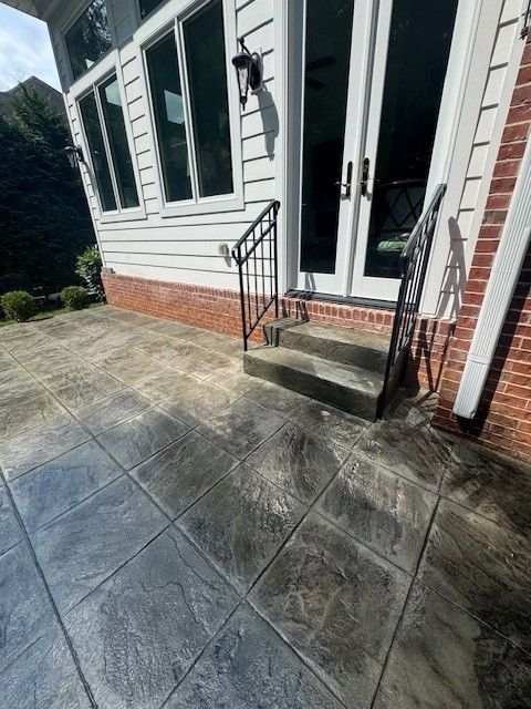 Comparison of a concrete patio before and after cleaning. The bottom half is clean, lighter, and more visible.