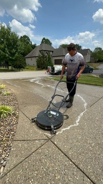 A man is cleaning a driveway with a machine. - Bourbon City Softwash - Louisville, KY