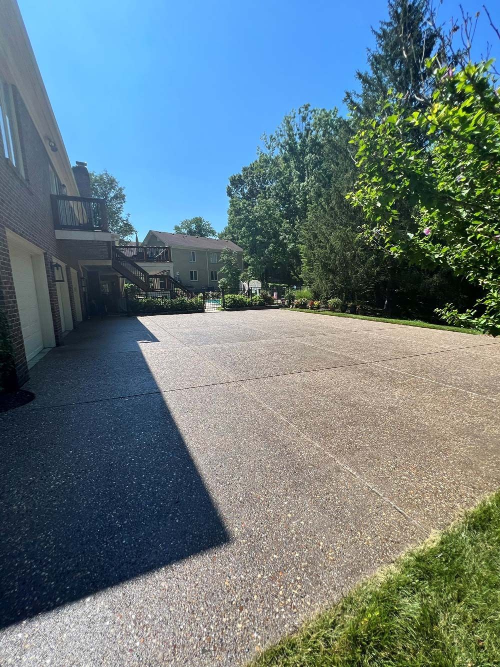 A large driveway with a house in the background and trees in the foreground. - Bourbon City Softwash - Louisville, KY
