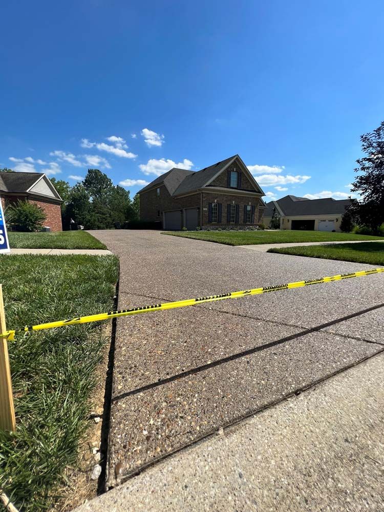A brick house with a concrete driveway surrounded by yellow tape. - Bourbon City Softwash - Louisville, KY