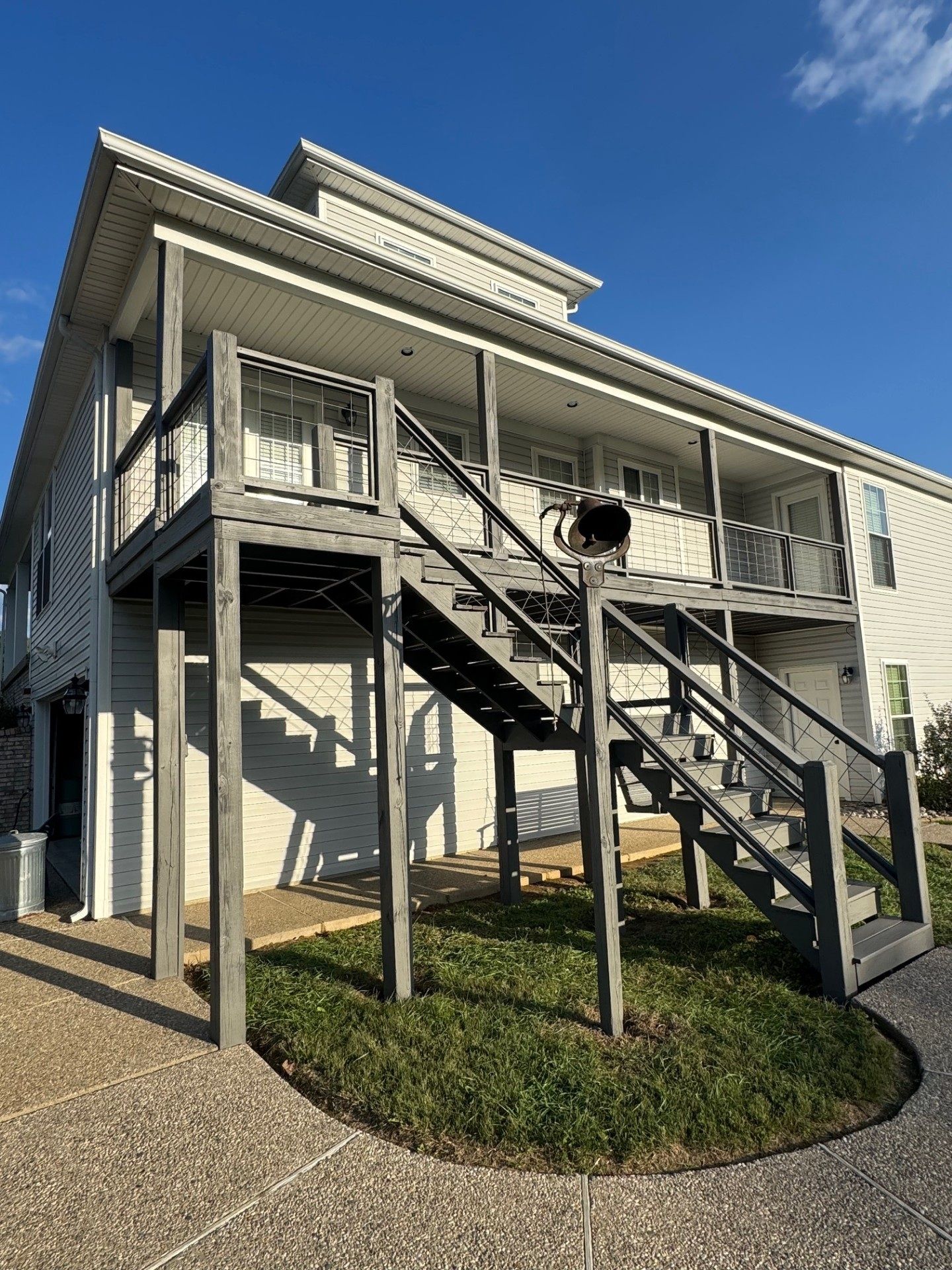 Gray wooden stairs leading up to a two-story apartment building with light-colored siding.