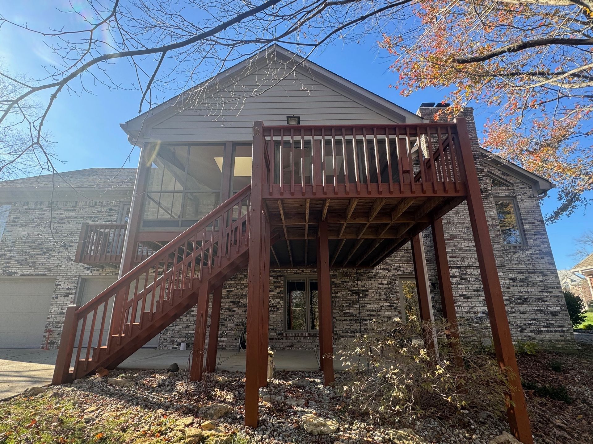 A large stone house with a wooden deck and stairs.