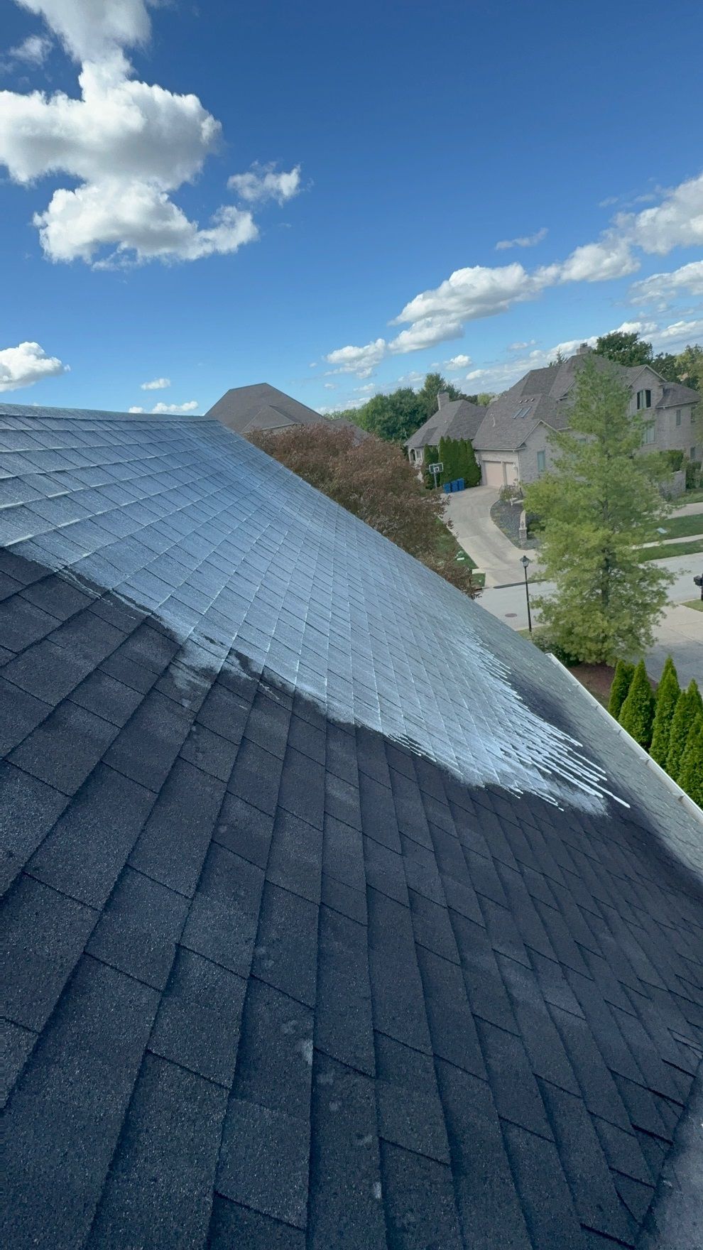 A roof is being painted on a sunny day.
