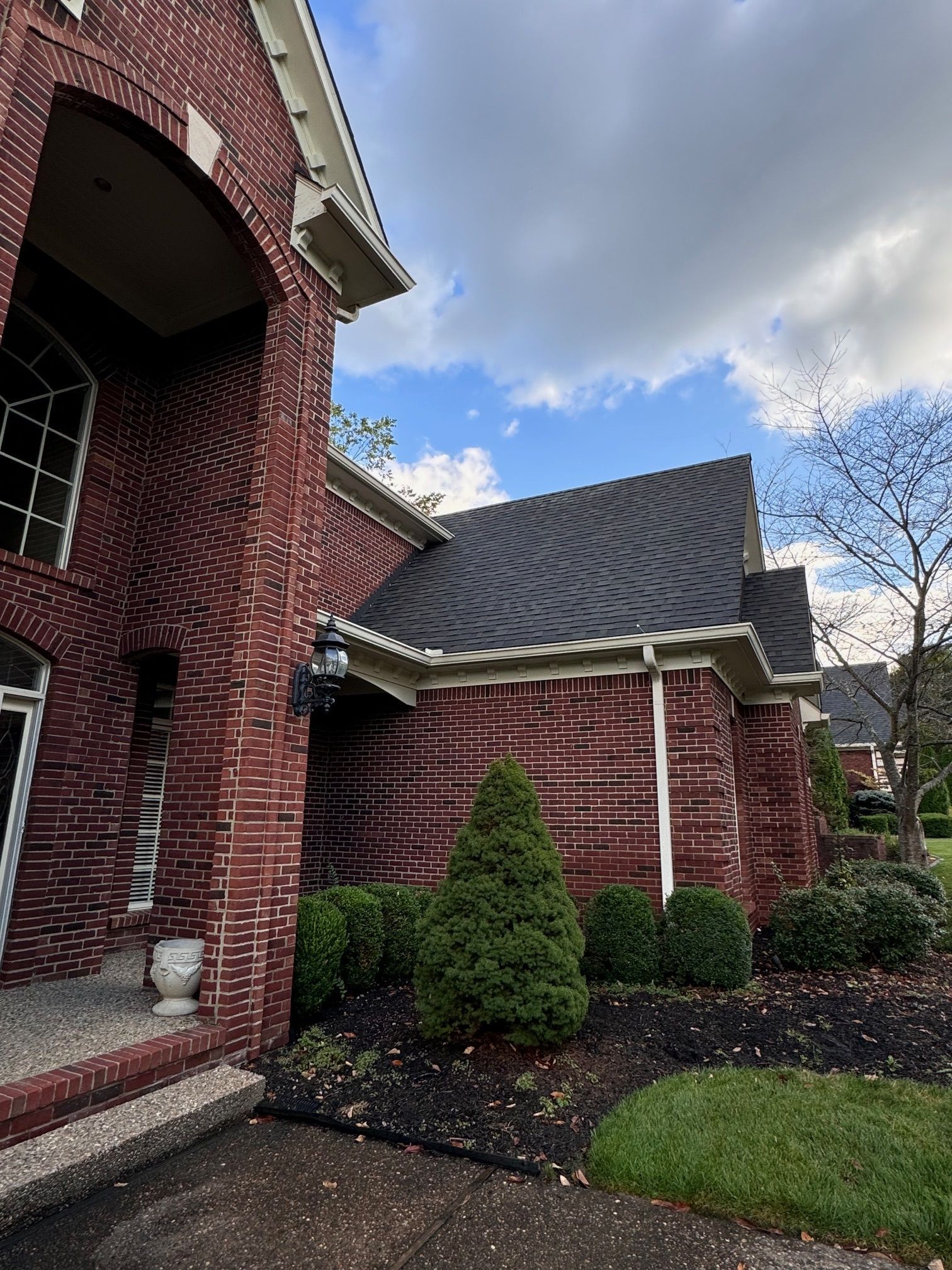 A large red brick house with a black roof and a large porch.