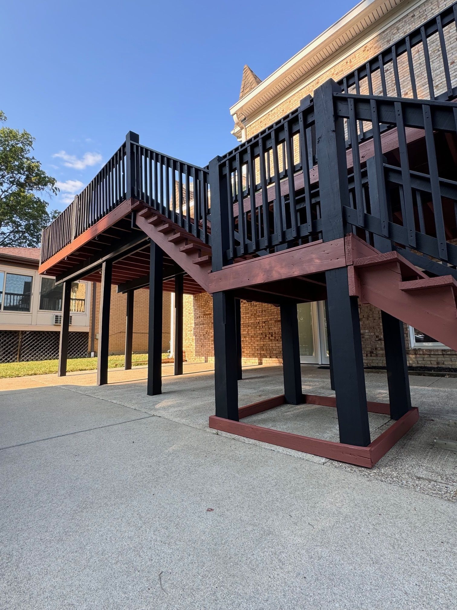A wooden deck with stairs leading up to it is in front of a house.