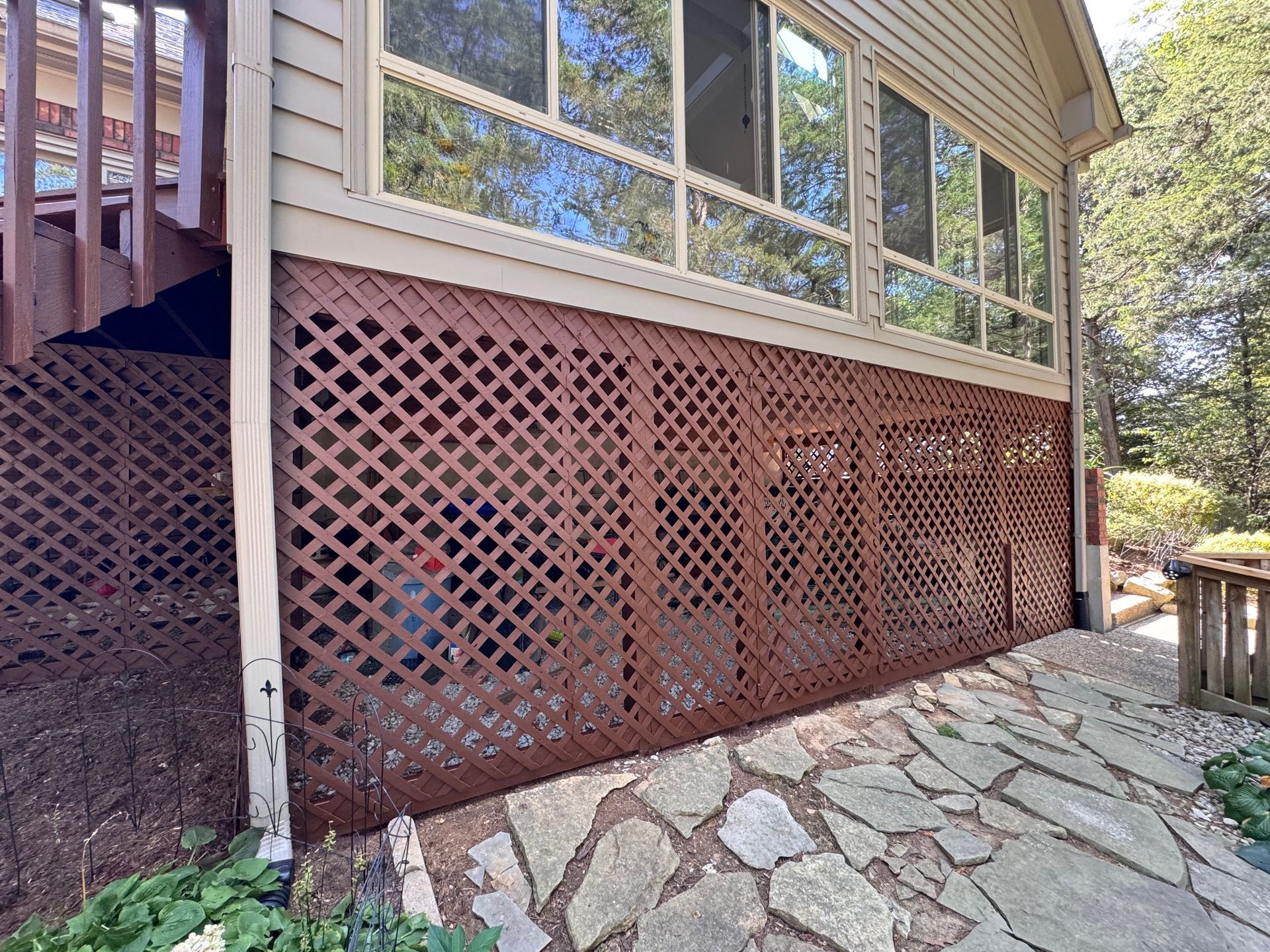 The side of a house with a wooden fence and stairs.