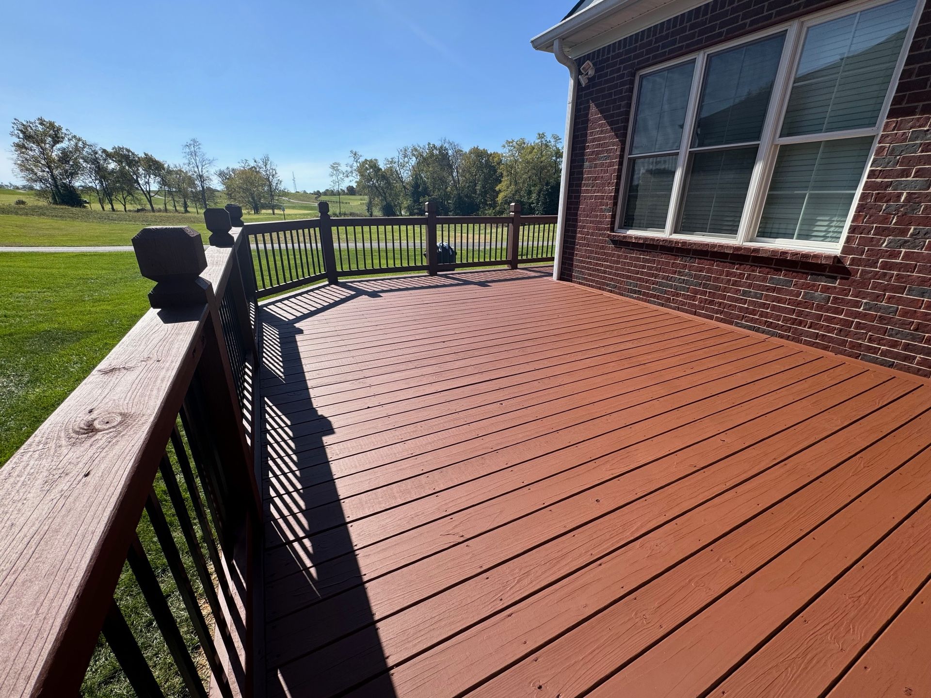 A Large Wooden Deck in Front of A Brick House