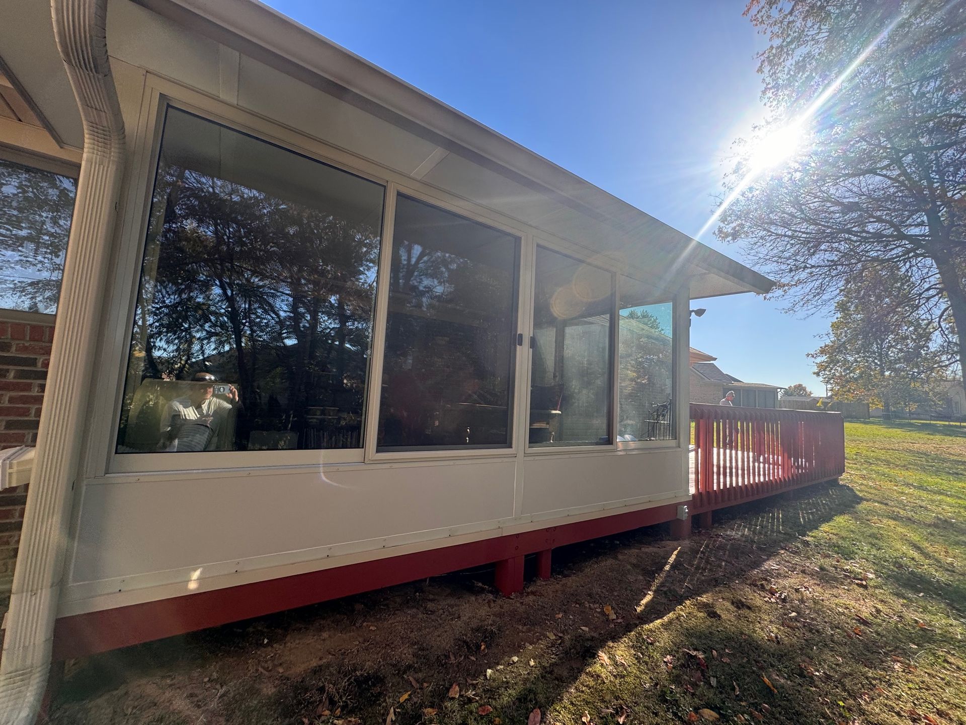 A white house with a red deck and a lot of windows.