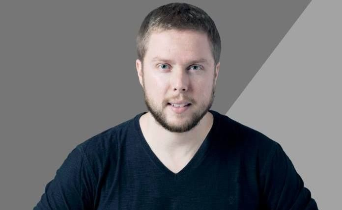 Aerial view of a resort with a large pool, cabana, and buildings with green surroundings and palm trees.