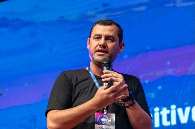 Um homem está falando em um microfone em frente a uma tela que diz itiviologia