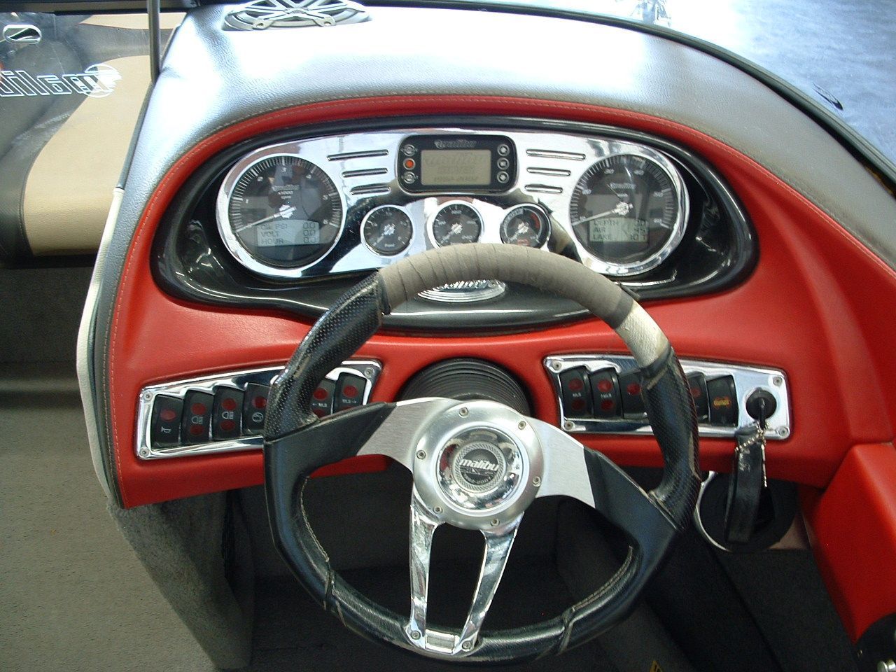 The dashboard of a boat with a steering wheel