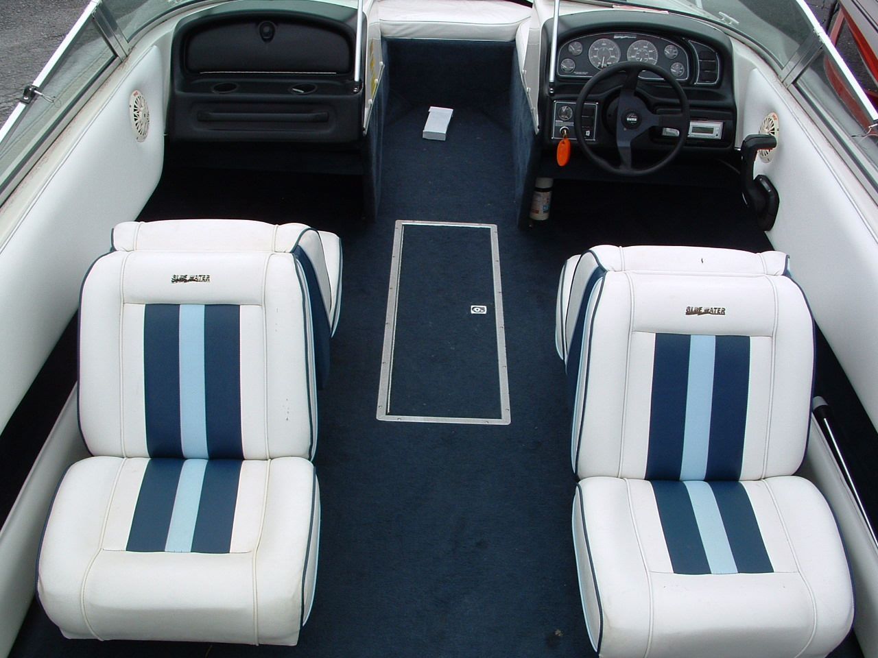 The inside of a boat with seats and a steering wheel