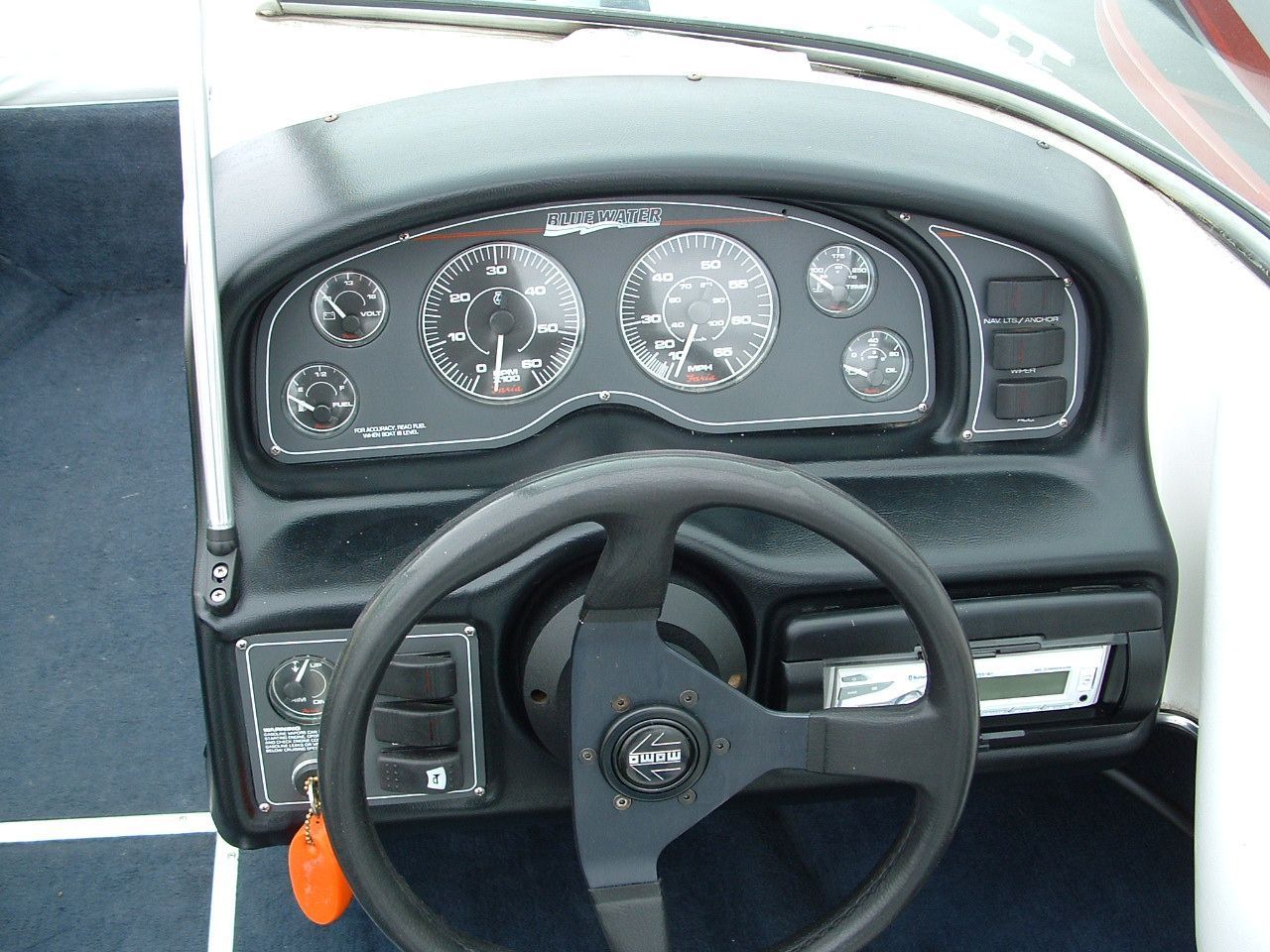 The dashboard of a boat with a steering wheel