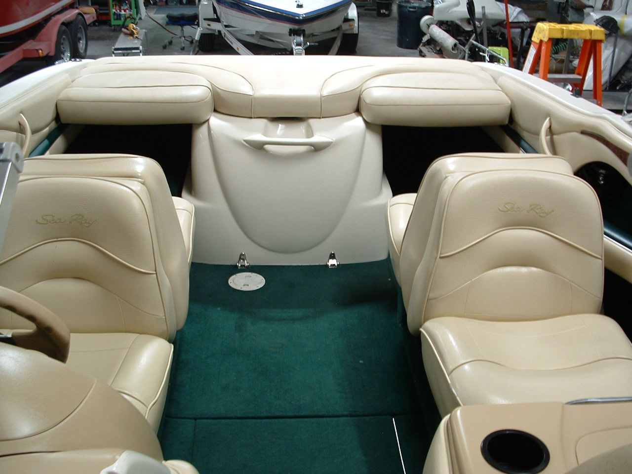 The inside of a boat with tan seats and a green carpet