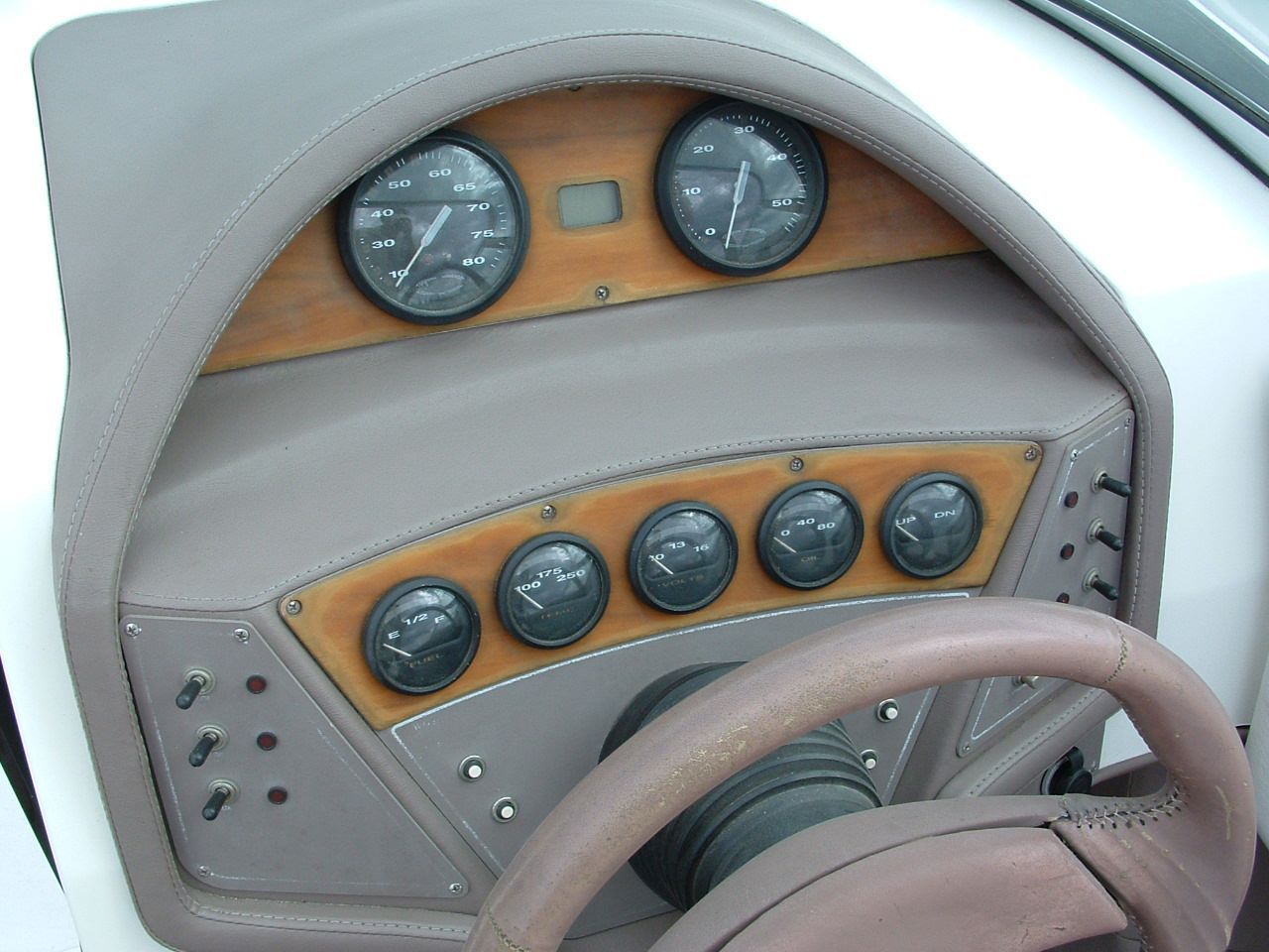A close up of a boat dashboard with a steering wheel